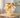Make Way for Ducklings baby gift basket in a yellow pail with a duck plush, storybook and embroidered duck bib and burp cloth on a nursery table