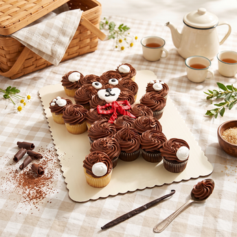 Bear Cupcake Cake of pull apart cupcakes piped in brown buttercream to form a bear with a friendly face, on a gingham covered table