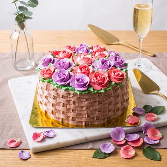 Blooming Basket Cake with a pink basketweave buttercream base and pink and purple buttercream roses on top, on a marble board