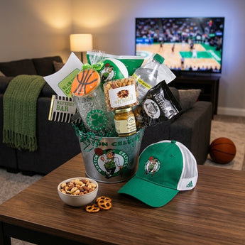 Boston basketball fan gift bucket with cap, snacks and tumbler on a den coffee table during game night