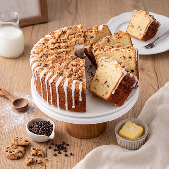 Chocolate Chip Crumb Cake with buttery crumb topping and a light drizzle, sliced to show the chocolate chips, on a white plate