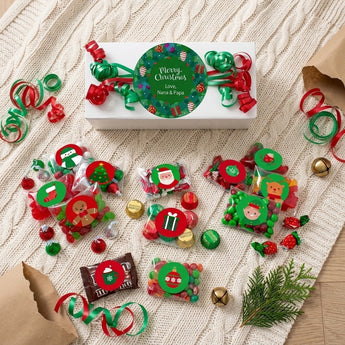 Overhead flat lay of a personalized Christmas candy gift box with character candy bags on a cream knit blanket