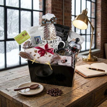 Coffee break gift with latte mug, French press, biscotti and chocolates on a loft writing desk