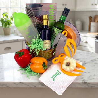 Deluxe salad kit gourmet gift with vinaigrette cookbook, whisk, dressing shaker, balsamic and wine vinegar, garlic press and salad hands, in an orange salad spinner bowl on a sunny kitchen counter