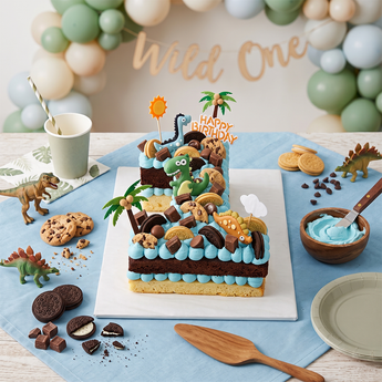 Dino Adventure Number Cake: buttercream number cake with dinosaur toppers, palm trees and sweet treats