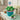 Easter cupcake bouquet with green grass buttercream cupcakes and speckled candy eggs in a teal pail, styled on an entry console with a woven basket and narcissus