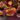 Halloween Basket Cupcake Bouquet of 19 cupcakes domed in a round wicker basket, orange, purple, green, yellow and chocolate buttercream swirls with Halloween sprinkles, a buffalo check ruffle and a Happy Halloween ghost topper, on a party table with candy jars and black pumpkins