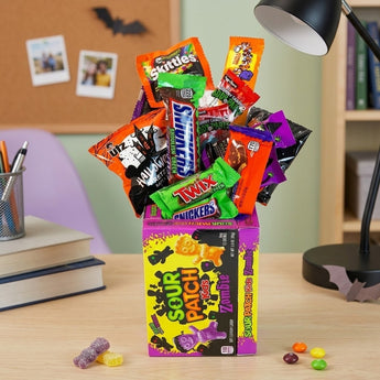 Halloween sweet candy bouquet of full size candy bars and Halloween snack bags fanned from a candy carton on a desk