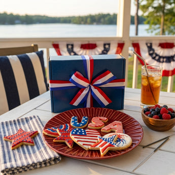 Hand Decorated 4th of July Sugar Cookies, USA, flag and star sugar cookies on a red plate with a blue gift box, on a lake house porch table