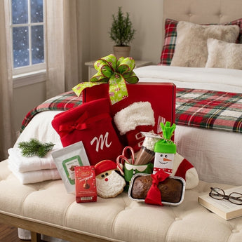 Holiday Snuggles gift with a monogrammed fleece blanket, cocoa mug and holiday treats on a guest bedroom bench