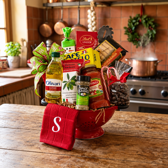 Italian Holiday Feast gift in a red colander with olive oil, pasta sauce, coffee and a monogrammed towel, on a rustic kitchen table