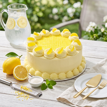 Lemon Delight Cake with lemon buttercream swirls and lemon glaze on an outdoor brunch table