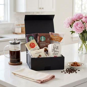 Mother's Day Coffee Gift Box, a black box of coffee, caramels and a Best Mom Ever mug, on a quartz kitchen counter with pink peonies