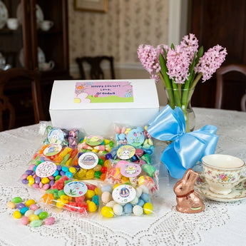 Personalized Easter Candy Gift Box, a white gift box with a personalized label and ten bags of Easter candy, on a lace covered dining table