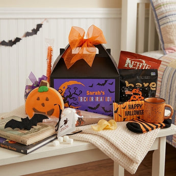 Personalized Halloween gable box of treats with a printed name panel, pumpkin cookie and snacks on a bench