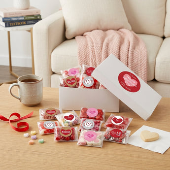 Personalized Valentine's Day Candy Gift Box, a white gift box with a Happy Valentine's Day label and bags of Valentine candy with heart stickers, on a coffee table in a bright living room
