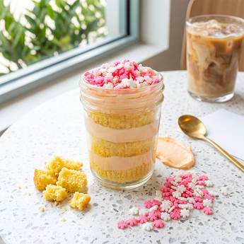 Pretty In Pink cupcake jar layered with vanilla cake and pink and white buttercream topped with pink sprinkles