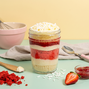 Strawberry cupcake jar layered with strawberry cake and vanilla buttercream with fresh strawberries alongside