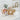 Stress relief spa package with a burlap cosmetic bag embroidered with the letter A, body wash, Honest lotion and body wash, a candle, a mesh pouf and tea, on a white bathroom vanity with a rolled towel and eucalyptus