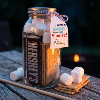 Sweet S'mores Kit jar with chocolate bar, graham crackers and marshmallows by a campfire