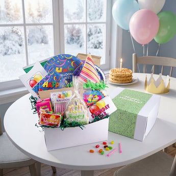 Birthday gift box with party hat, cake cookie and candy on a breakfast table with balloons on a snowy morning