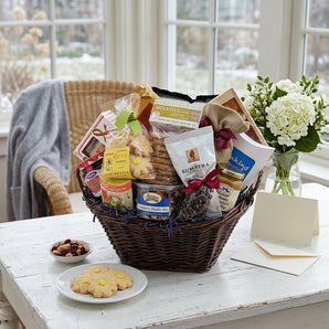 Thinking of You gourmet gift basket with cookies, coffee and snacks on a sunroom table with white hydrangeas