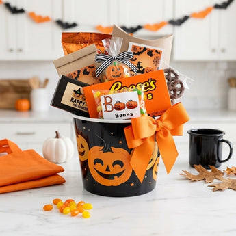 Trick or Treat Sweets in a black jack o lantern pail with an orange bow, filled with Halloween candy on a kitchen island