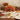 Turkey shaped cake with candy corn feathers on a pale yellow pedestal stand, styled on a cream linen Thanksgiving table with stacked plates, a rust napkin, a bowl of candy corn and a gold cake server