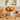 Turkey cupcake bouquet of seven buttercream turkey cupcakes in a mint pail with an orange ruffled collar, styled on a white oak kitchen table with cream plates, an amber napkin and a bowl of pecans