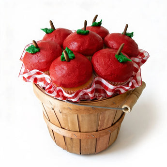 Red apple-shaped cupcakes in a wooden basket on a white background