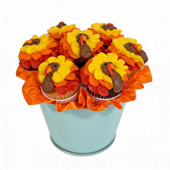 Cupcakes decorated like turkeys in a blue bucket on a white background