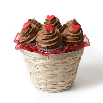 Basket of chocolate cupcakes with red heart decorations on a white background