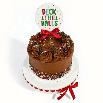 Chocolate Christmas sprinkles cake with a 'Deck the Halls' topper on a white background