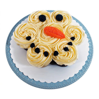 Cupcake decorated like a snowman on a white plate with a white background