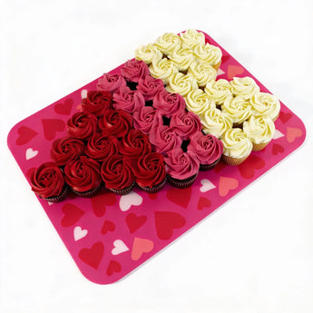 Cupcakes decorated with red and white frosting on a pink heart-patterned tray.