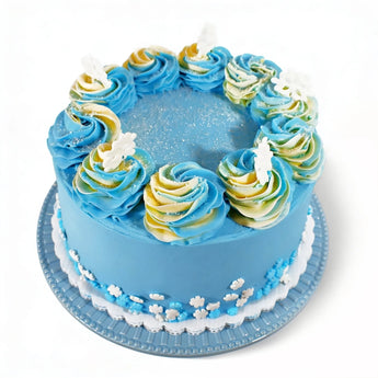 Blue winter-themed frosted cake with decorative swirls and white snowflakes on a white background