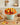 Turkey cupcake bouquet of seven buttercream turkey cupcakes in a mint pail with an orange ruffled collar, styled on a white oak kitchen table with cream plates, an amber napkin and a bowl of pecans