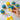 Graduation cupcakes with blue and yellow buttercream and yellow sprinkles on a marble counter, one vanilla cupcake held in hand with a bite taken, beside the Happy Graduation topper