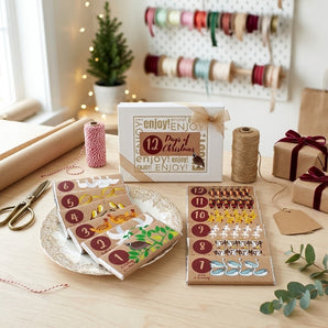 12 Days of Christmas candy bar set with twelve numbered illustrated chocolate bars and gift box on a holiday gift wrapping table