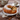 Chocolate Chip Bundt Cake dusted with powdered sugar and sliced to show the chocolate chips, on a white plate beside a teapot