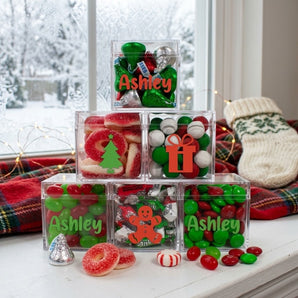 Personalized Christmas candy pyramid of six clear cubes with name lettering and holiday decals on a snowy window seat