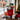 City Sidewalks Holiday Gift Tote Regular size: a red canvas tote printed with Boston in white script, filled with holiday snacks including CheeseSticks and a green coffee bag, with a Boston postcard book and a greeting card in front, styled on a dark wood table by a large window looking onto a snowy Beacon Hill brick street with a gas lamp