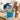 College clean up bucket in bright blue packed with Mr. Clean, Wet Ones, Post-it notes, Ajax, Oreos, Nutter Butter and snacks, on a dorm room desk on move in day with a laptop and moving boxes