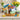 Deluxe Easter Gift Basket, a woven basket of Late July chips, Popcorners, candy and decorated Easter cookies, on a sideboard with yellow tulips
