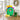 Easter Gift Basket Tote, a green tote basket of Easter candy and snacks with a yellow bow, on an entry bench beside rain boots