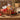 Wooden farm truck gift loaded with Boston's Best coffee, Ghirardelli chocolate, cocoa and a hand painted pumpkin sugar cookie, styled on a farm stand counter with apple crates and corn stalks