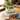 Floral cake with bold red, blue and yellow piped buttercream flowers on top and a green shell border