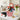 Graduation congratulations gift in a red striped popcorn bucket with a teddy bear in a grad cap, a Class of 2026 lollipop and Jelly Belly, on a kitchen island with a cap and diploma