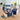 Star of the Day Edible Gift Basket Regular size: one white gift box with a navy Star of the Day band, filled with treats tied with blue ribbon including a Star Bar, Lucky Beans and mixed nuts, with a matching closed navy Star of the Day box beside it, styled on a light wood office desk with a laptop and yellow tulips
