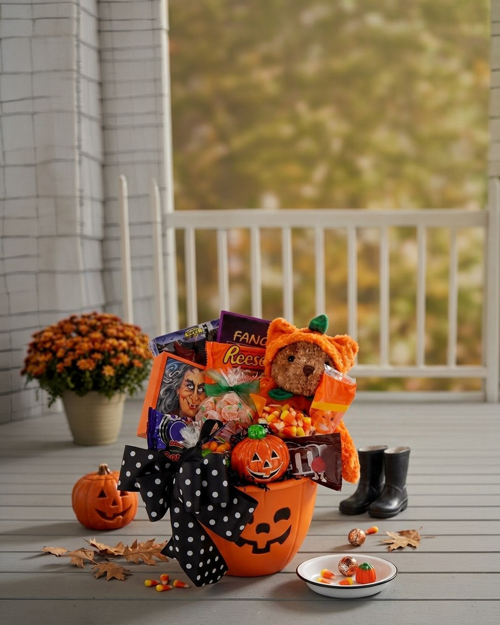 Trick or Treat Halloween Gift Basket on an autumn porch with mums and a carved pumpkin